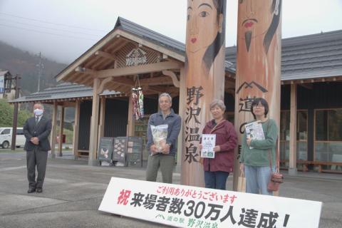 道の駅の道祖神モニュメント前で、30万人目の認定証・記念品を手に佐藤さん一家