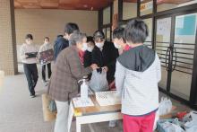 学校を訪れて子どもたちと談笑しながら炭を買う住民も