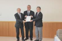 飯山市第6次総合計画基本構想素案を答申した坪根審議会長(中央)